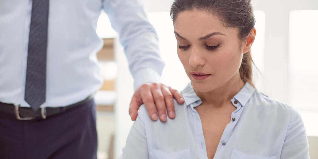 Woman looks uncomfortable as a man puts his hand on her shoulder