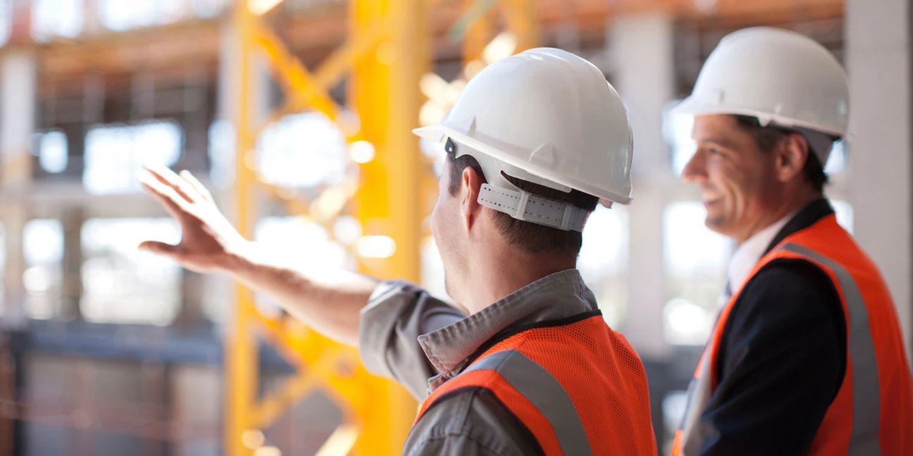 Two contractors on a building site, seen from behind