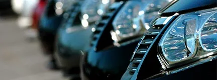 Close-up of parked rental cars in a row, highlighting shiny headlights and grills.