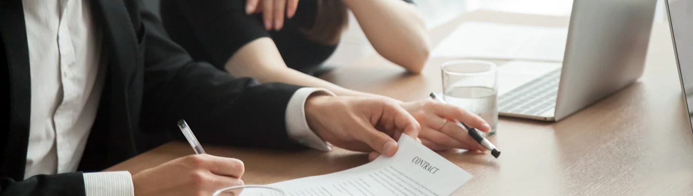 Businessman and woman look over the contract on the desk with a laptop.