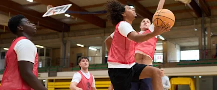 Basketball players jumping for the ball in a gym. Specialized sports facility insurance protects competitive environments.