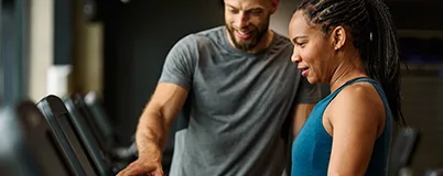 Two people in a gym looking at a clipboard.