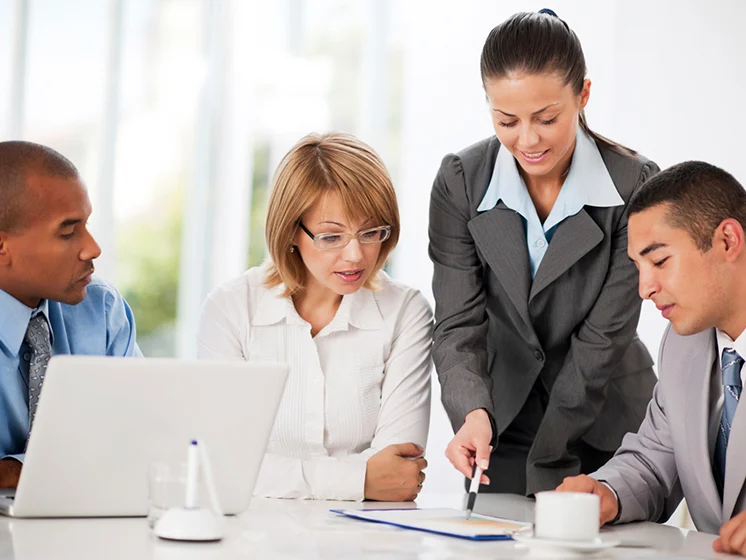 A group of 4 professionals look at something (cropped from image)