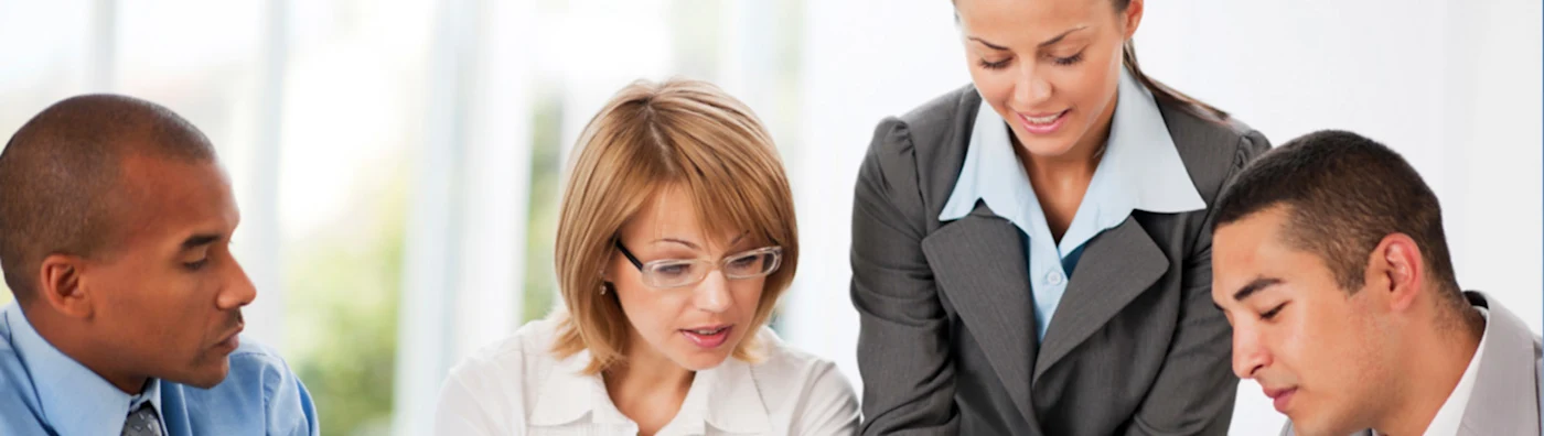 A group of 4 professionals look at something (cropped from image)