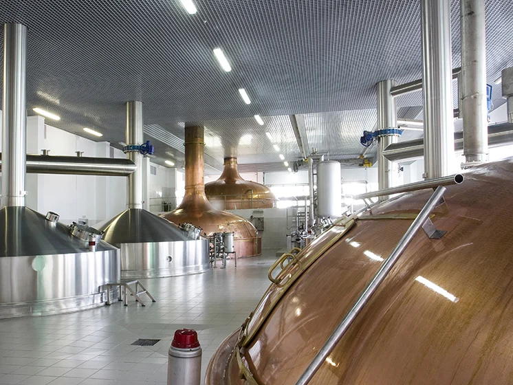 Interior of a brewery with large stainless steel and copper fermentation tanks and equipment.