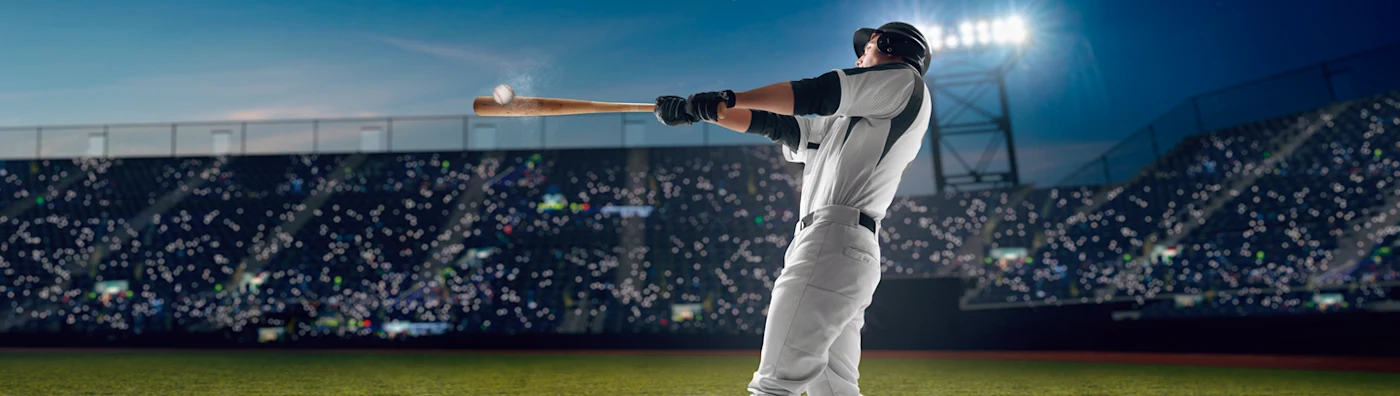 Baseball player hits the ball in a packed, brightly lit stadium during a night game.