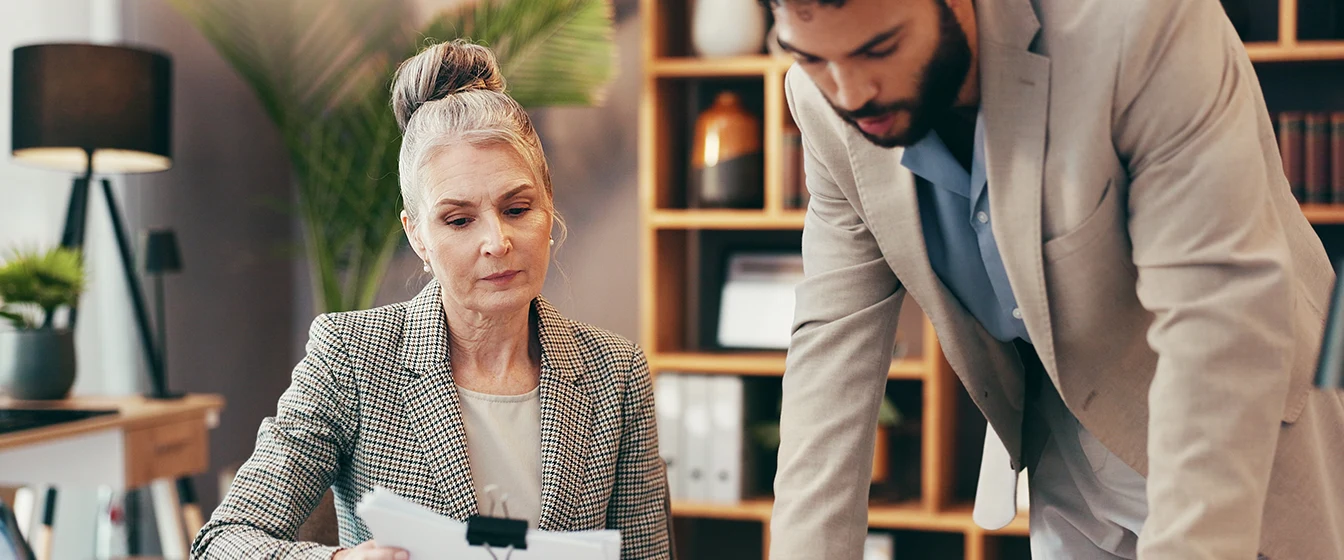 An insurance agent explaining a commercial policy to their client in an office setting.