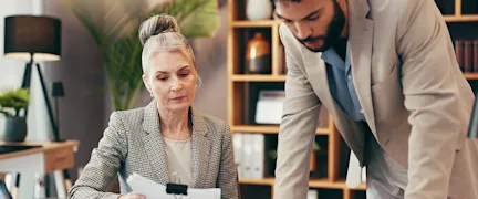 An insurance agent explaining a commercial policy to their client in an office setting.