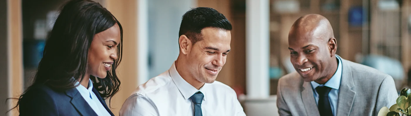 Close-up of three diverse business people looking at something on a laptop screen.