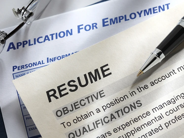 Close up of a resume and job application form with a pen resting on top.