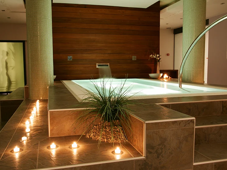 Indoor spa area with a lit jacuzzi, soft candlelight, modern décor, and relaxing ambiance.