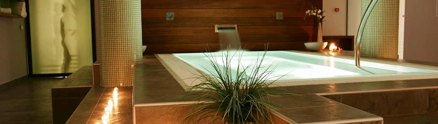 Indoor spa area with a lit jacuzzi, soft candlelight, modern décor, and relaxing ambiance.
