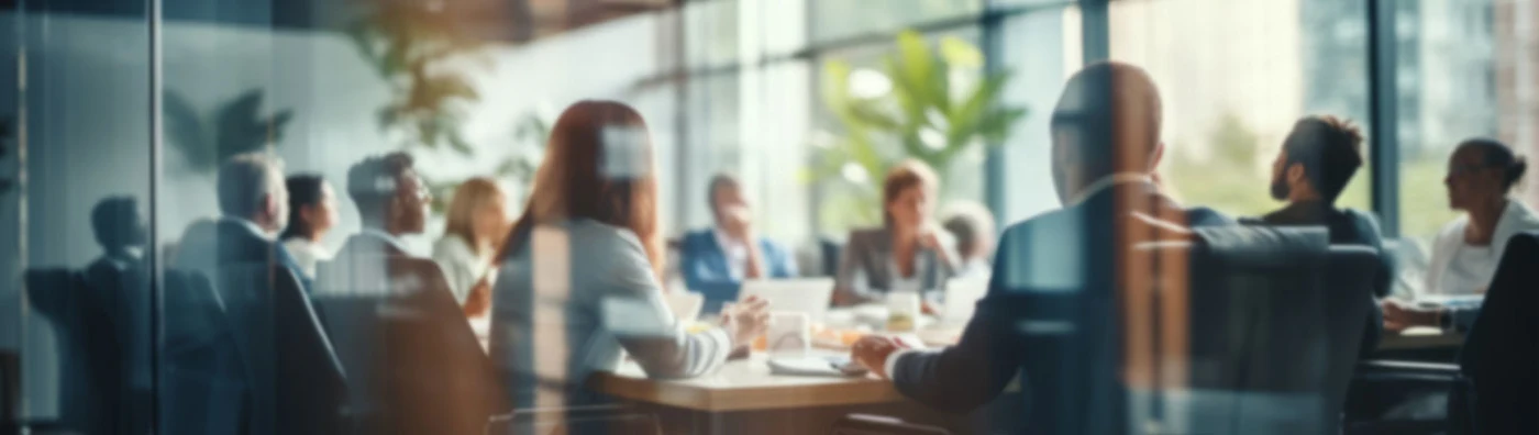 Business professionals in a modern glass-walled conference room during a daytime meeting.