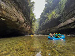 People in an inflatable blue raft paddle down a river.