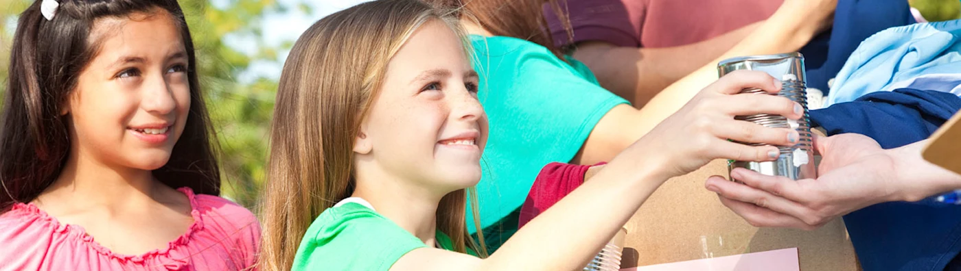 Smiling children donating canned goods at a community or nonprofit collection event.