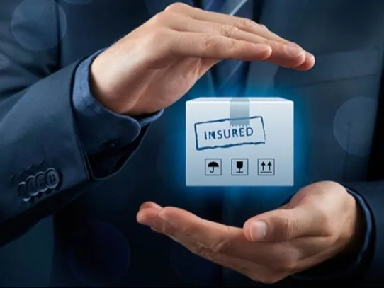Businessman holds glowing "Insured" cube icon, symbolizing protection and coverage.
