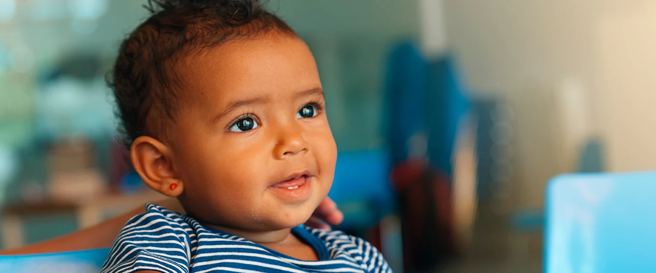 A smiling toddler girl sits at a table with blocks.