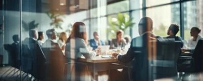 Business professionals in a modern glass-walled conference room during a meeting.