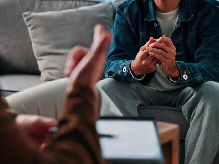 A mental health counselor and their client talk during a therapy session