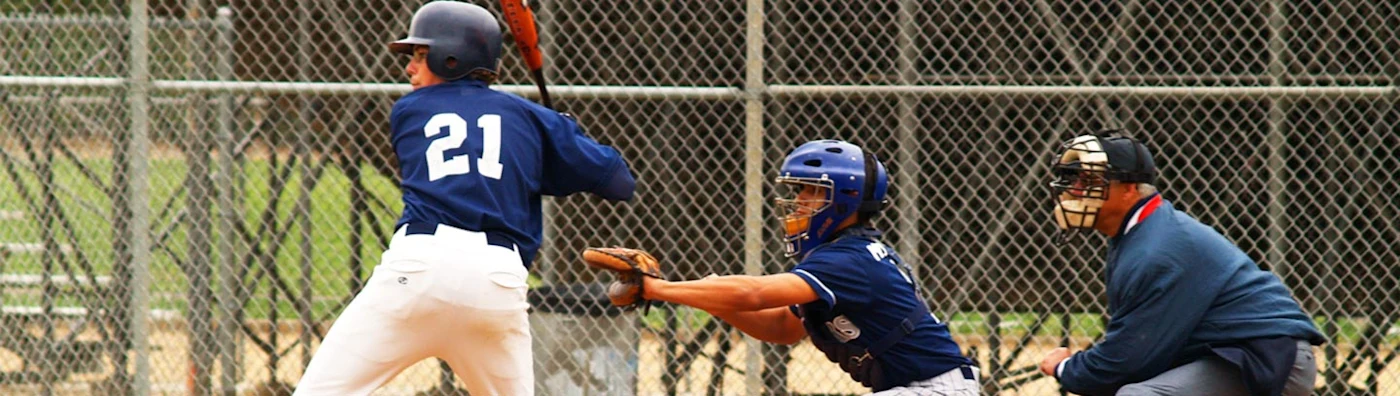 Baseball game with batter, catcher, and umpire in action at an amateur sports field.