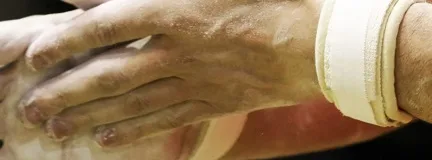 Close up of chalk-covered hands clapping before a gymnastics routine.