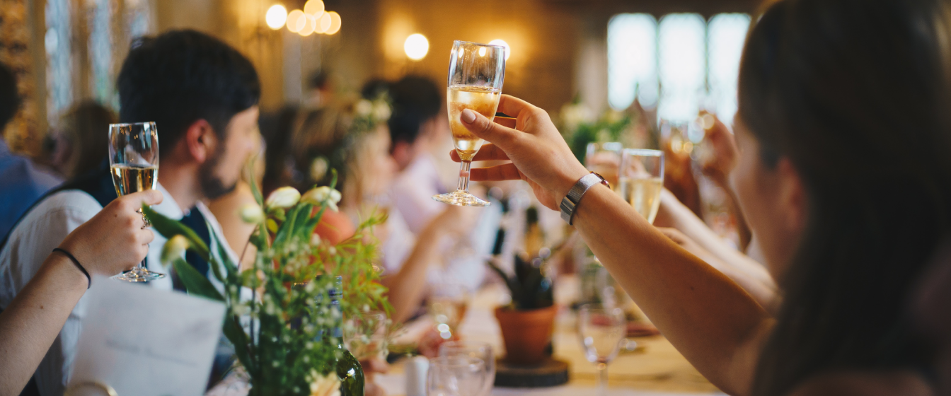 Wedding guests raise a toast at an evening reception, relaxed because they have wedding venue insurance.