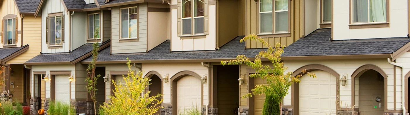 Row of modern townhouses with small front yards, garages, and neatly maintained landscaping.