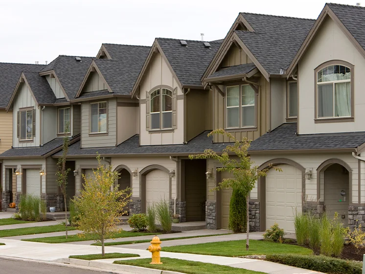 Row of modern townhouses with small front yards, garages, and neatly maintained landscaping.