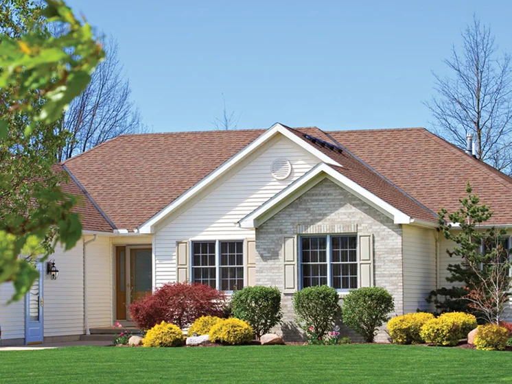 Single-story suburban home with well-maintained lawn, shrubs, and colorful landscaping in front.