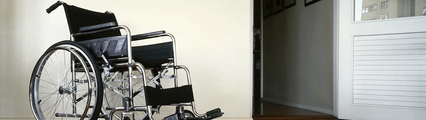 Empty wheelchair positioned near an open doorway in an indoor setting.