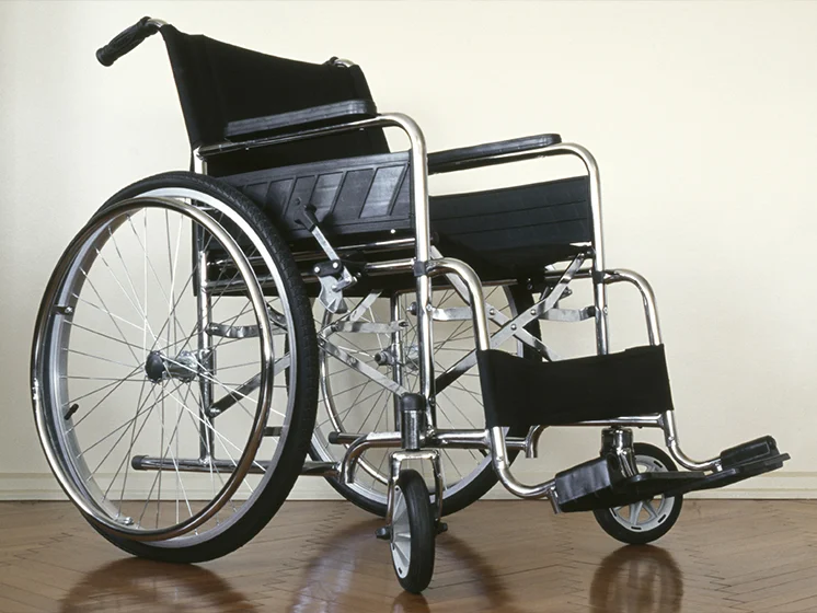 Empty wheelchair positioned near an open doorway in an indoor setting.