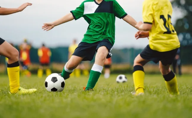 Young people play soccer on a grassy field. Amateur sports insurance can cover players, coaches, and volunteers.
