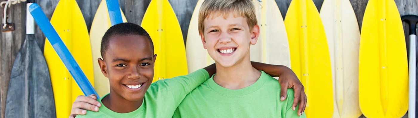 Two kids in front of row of yellow surf boards