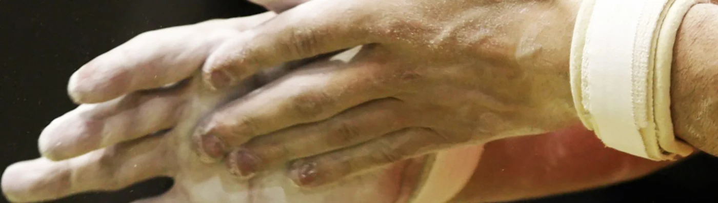 Close up image of chalk-covered hands clapping before a gymnastics routine.