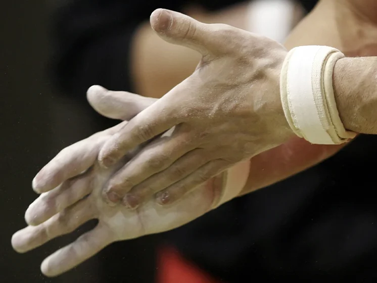 Close up image of chalk-covered hands clapping before a gymnastics routine.