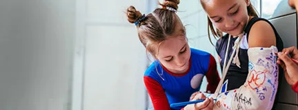 One young girl signs another child's cast