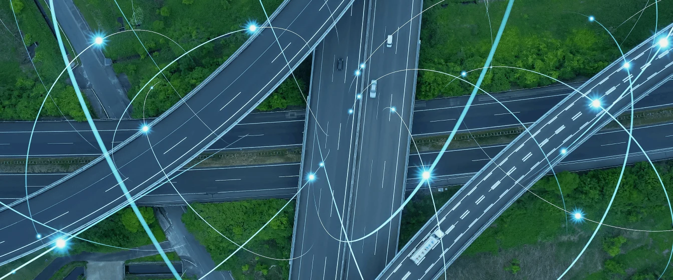 Cars and trucks driving on a highway interchange while transmitting data.