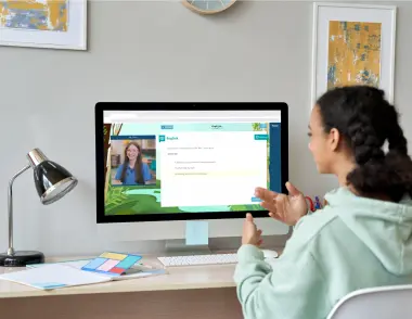 A teenage girl is working on a computer at a desk - on screen there is an Explore Learning tutor with an example question. 