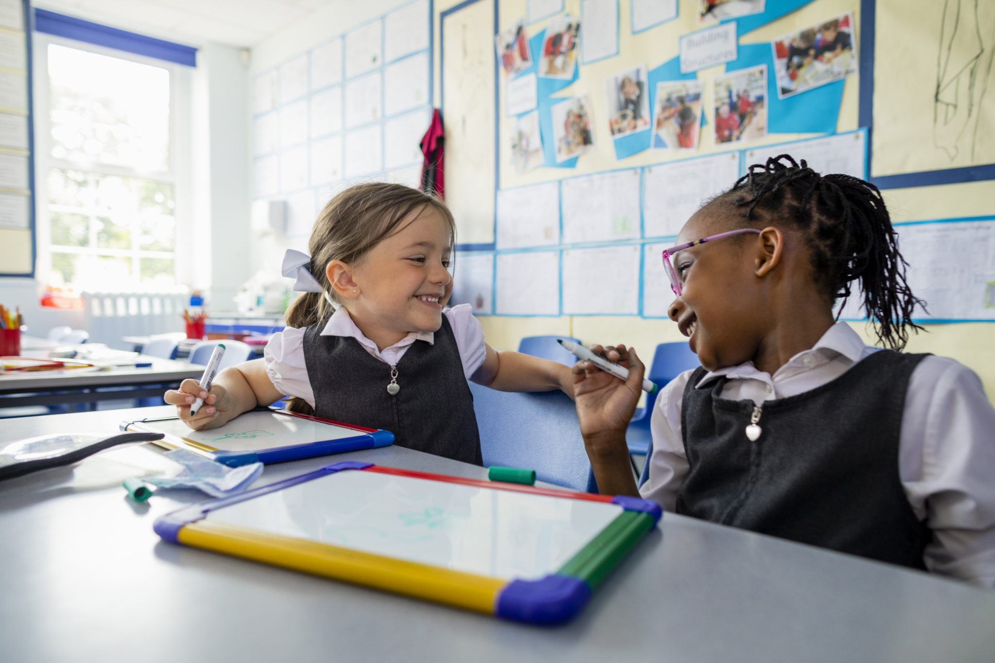 2 girls colouring together in school