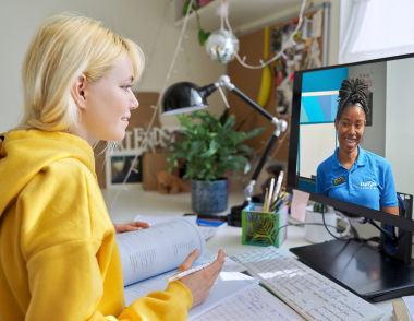 A teenage girl sits at a computer with an Explore tutor on screen.