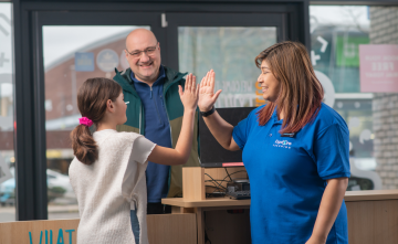 A child high fives with their tutor as the caregiver watches. 