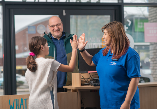 A child high fives with their tutor as the caregiver watches. 