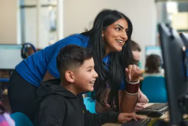 A female tutor works with a young boy to support him in his learning. 