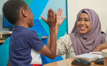 A child and their tutor high fiving.