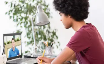 A teenage child is sitting at a desk with an open laptop in front of him. On screen there is an Explore tutor. 