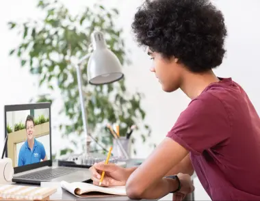 A teenage child is sitting at a desk with an open laptop in front of him. On screen there is an Explore tutor. 