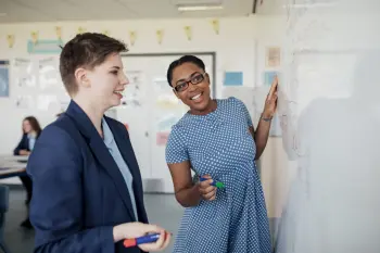 Teenager and a teacher working on a whiteboard together