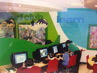 Picture of the 1st centre with children using computers and a tutor helping them