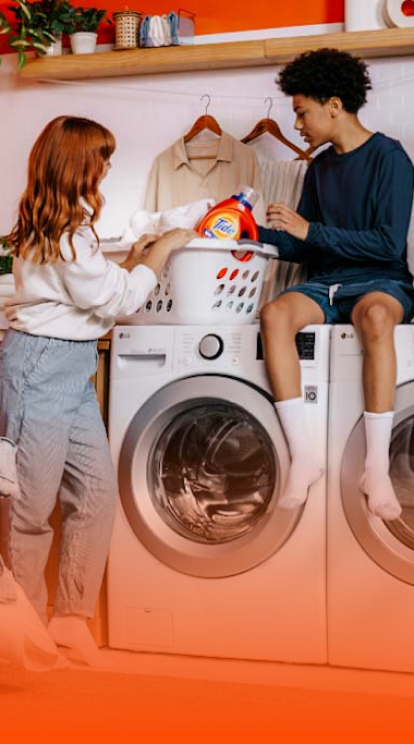 A group of teenagers sitting on a washing-machine prepared to do laundry