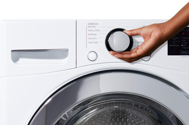 A hand changing the setting on a washing machine
